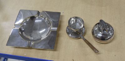 un cendrier en argent, une cuillère et un repose-cuillère posés sur une table