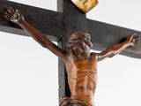 a statue of jesus on the cross with a clock in the background