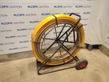 a yellow hose on a cart in front of a wall