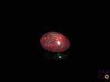 a close up of a red oplite stone on a black surface