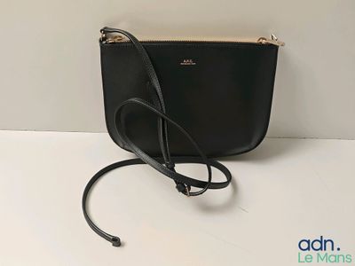 un sac à main noir posé sur une table près d'un mur blanc