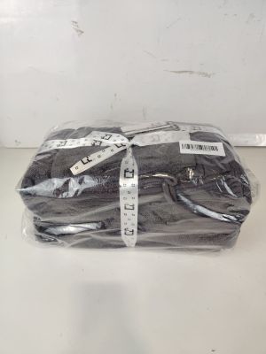une chemise noire emballée dans du plastique, posée sur une table blanche