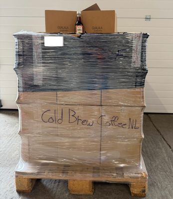 Des cartons de café infusé à froid sont empilés sur une palette dans un entrepôt