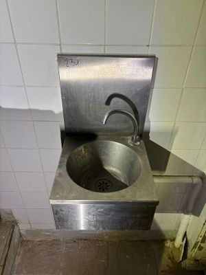 a stainless steel sink in the corner of a bathroom