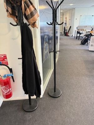 un porte-manteau sur lequel est posé un parapluie, à côté d'un extincteur