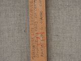 a wooden ruler with writing on it hanging on a rope