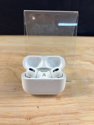 des AirPods de la marque Apple posés sur une table en bois, à côté d'une boîte transparente