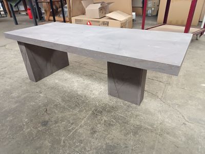 une table en béton dans un entrepôt, avec des cartons en arrière-plan