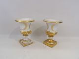 pair of white and gold vases sitting on top of a white table