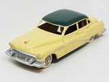 a yellow toy car with a green roof on a white surface