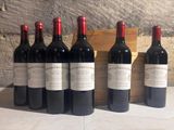 six bottles of red wine are lined up in front of a wooden crate