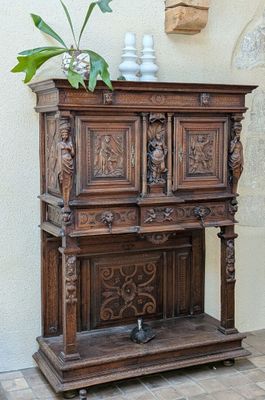 a wooden cabinet with carvings on the front and a potted plant on top of it