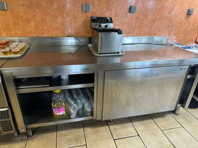 un plan de travail en acier inoxydable dans la cuisine d'un restaurant, avec une bouteille de soda