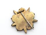 a close up of a gold brooch with a metal pin on it