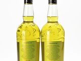 two bottles of olive oil sit side by side on a white surface