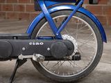 a close up of a blue motorcycle parked in front of a brick wall