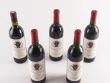 six bottles of wine are lined up on a white surface