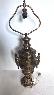 une vieille lampe en laiton surmontée d'une clochette, posée sur une table