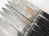 several knives are lined up in a row on a white surface