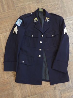 navy blue military jacket with patches and buttons on a wooden floor