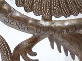 a metal sculpture of a bird with a name written on it