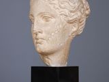 a close up of a sculpture of a woman ' s head on a wooden table
