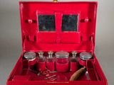 a red suitcase with silverware in it on a table