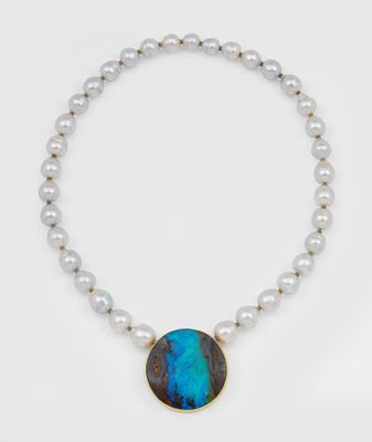 un gros plan sur un collier composé de perles et d'une pierre bleue