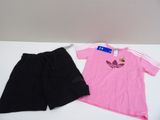 une chemise rose et un short noir posés sur une table blanche, suspendus à un cintre