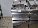 two deep fryers sitting on top of a stainless steel counter