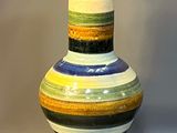 a multicolored vase sitting on a gray surface