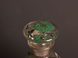 a glass bottle with a green and black design on it