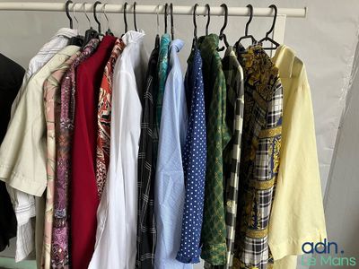 a lot of shirts hanging on a rack in a room