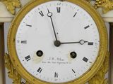 a gold clock with a white face on a table