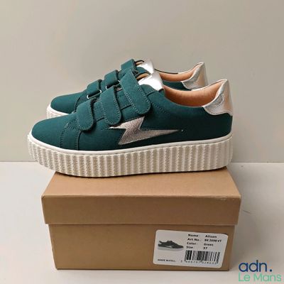 a close up of a pair of green sneakers on a box