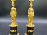 deux vases dorés et noirs ornés de statuettes, posés sur une table