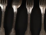 six forks are lined up in a row on a black surface