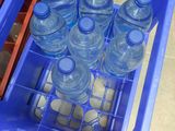 a blue plastic container filled with water bottles on a tiled floor