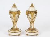 une paire de vases blancs et dorés posés sur des socles, sur fond blanc