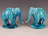 pair of blue ceramic elephant figurines on stand on grey background