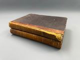 two old books sitting on top of each other on a table