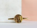 a gold ring with a coin on top of a marble block