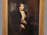 tableau représentant un homme en costume noir et chemise blanche, assis sur une chaise