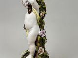 a figurine of a woman holding a bird on top of a tree