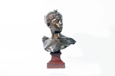 un buste en bronze représentant un jeune homme, posé sur un socle rouge