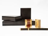 deux boîtes noires ornées de dorures, sur lesquelles est posé un stylo