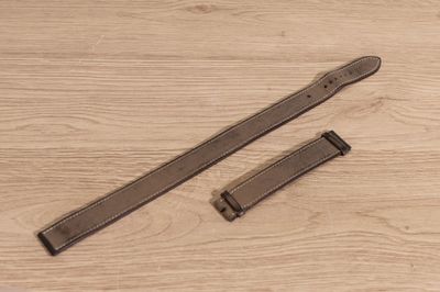 two pieces of leather on a wooden surface with a watch strap