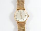 a gold watch with a white face on a white surface