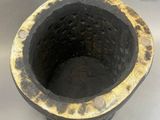 a close up of a black and gold vase on a table