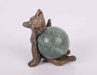 statue d'un ours tenant une boule de pierre verte sur une surface blanche